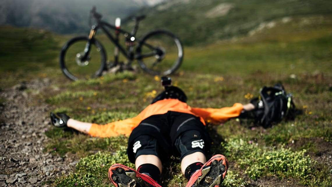 Exhausted mountain bike rider lying down in grass