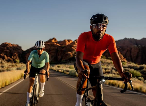 Lifestyle shot of two cyclists wearing helmets and sunglasses on road bikes