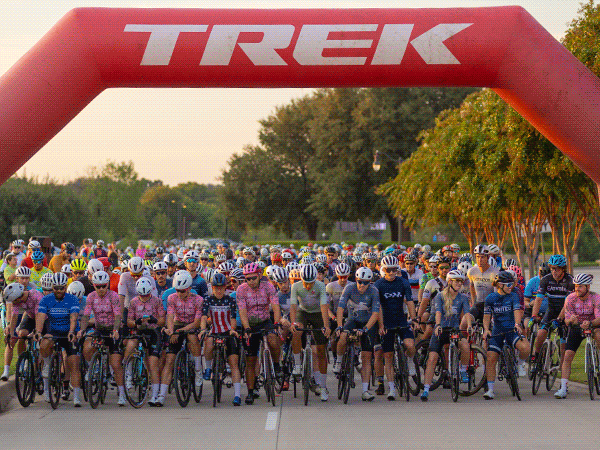 Cyclists crossing the Trek 100 finish line