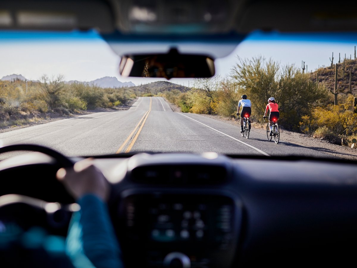 View from inside a car of cyclists riding ahead on the road