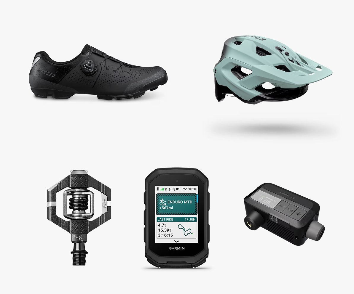 A collection of fresh MTB gear and accessories including a shoe, helmet, pedal, GPS computer, and rear light