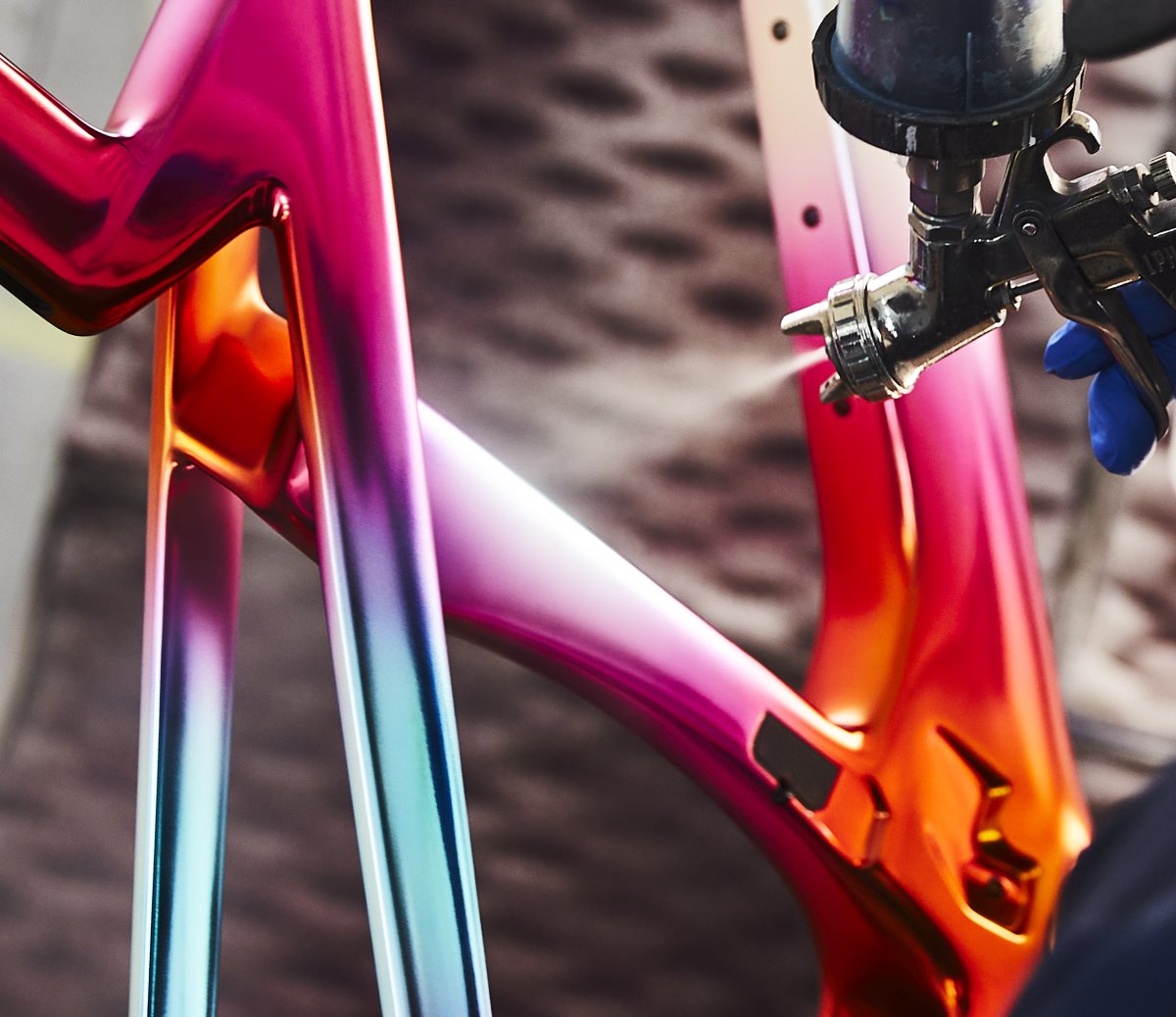 Painter airbrushing an iridescent pink and orange finish onto a Project One frame