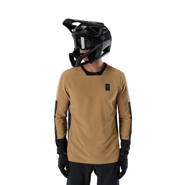 A model wears a tan and black Fox Racing long-sleeve MTB jersey with a full-face helmet