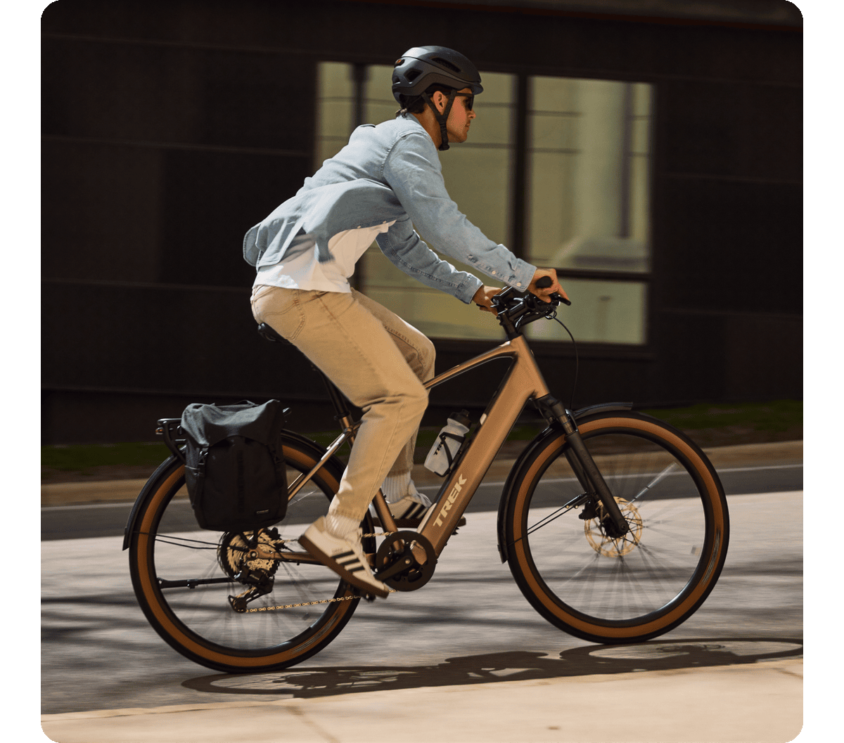 A cyclist wearing a helmet riding a Trek FX+ 2 e-bike through a city street