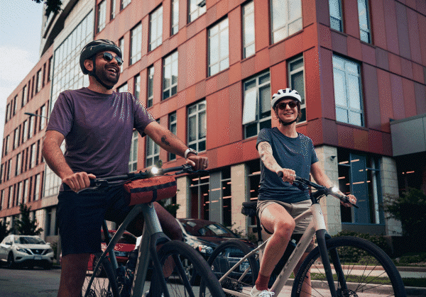 Two cyclists walking their bikes on a city street