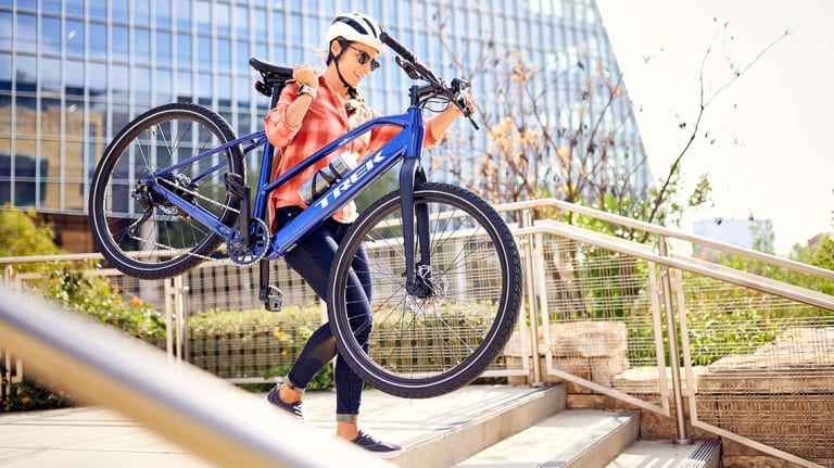 woman carrying trek dual sport 2 ebike